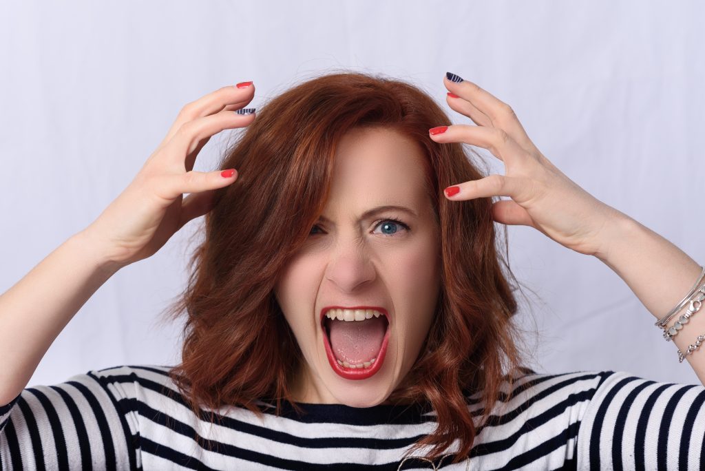 Angry red-haired woman grabbing her hair