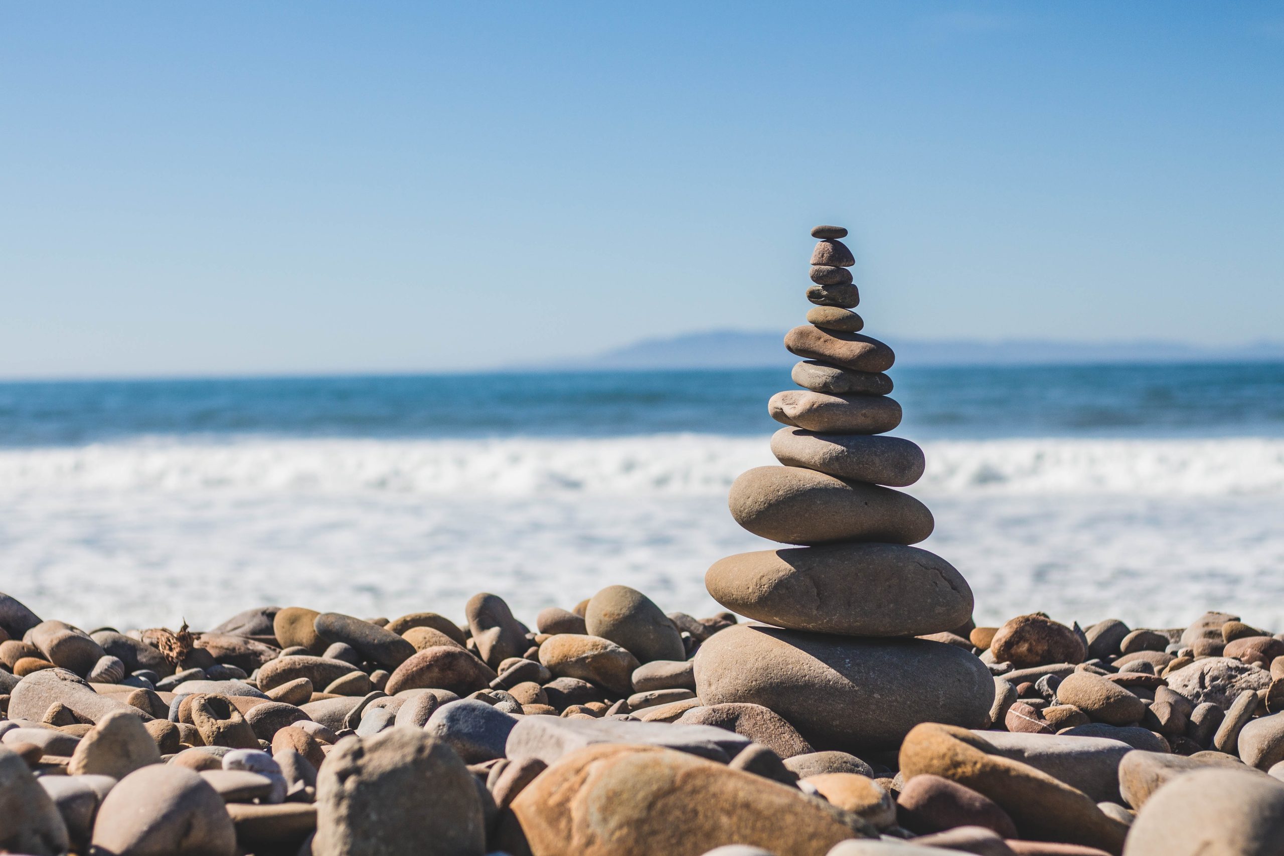 Pebble cairn on beach with ocean waves