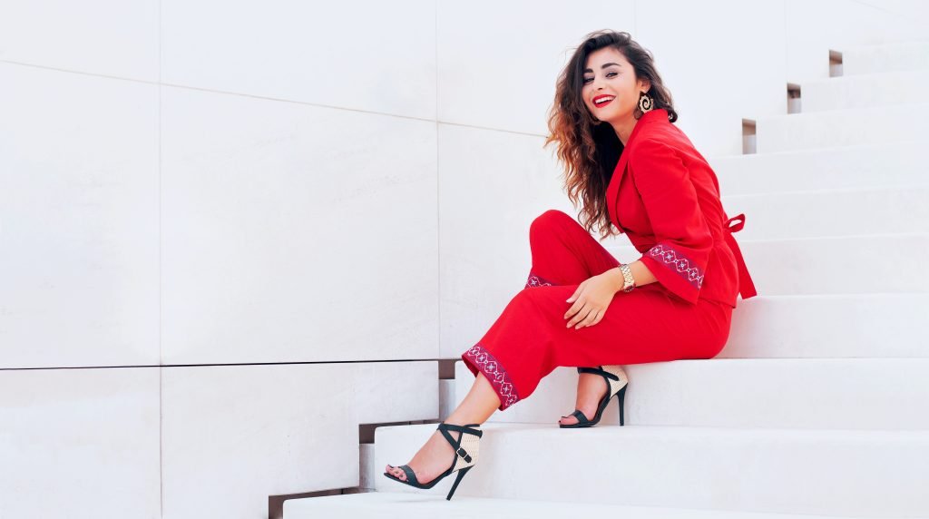 Smiling woman in red suit on white stairs