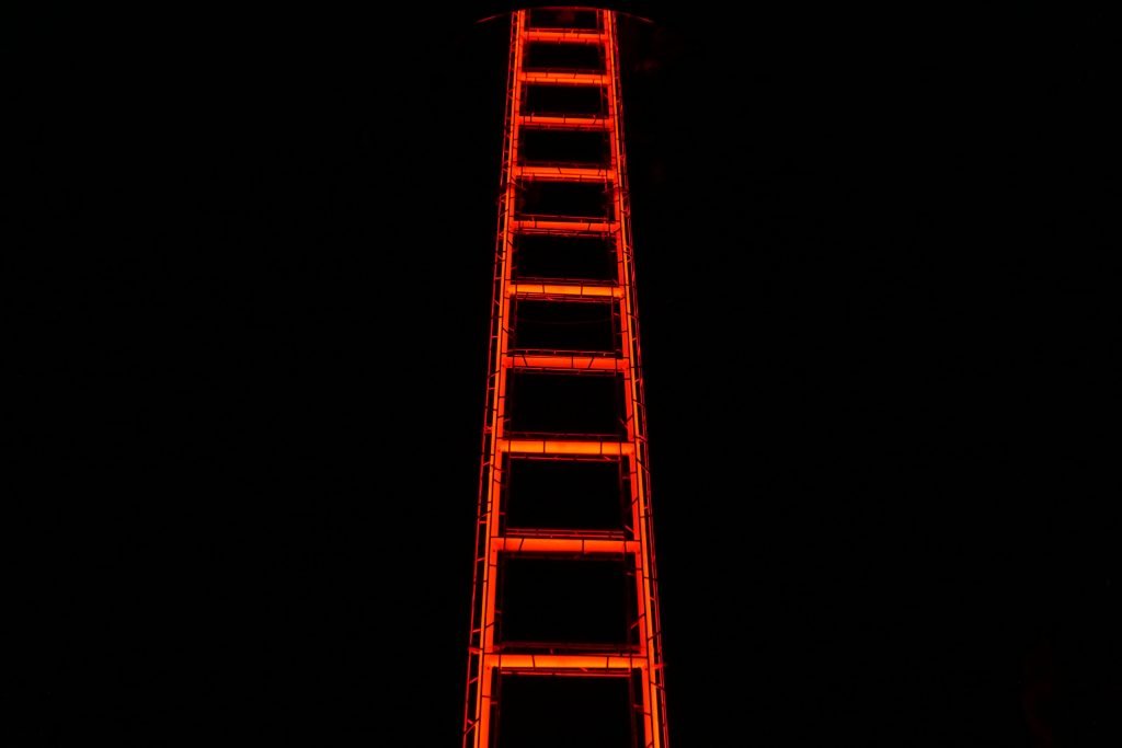Red illuminated ladder against black background