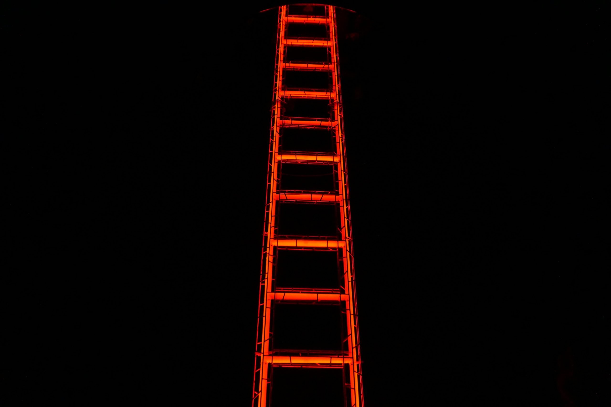 Red illuminated ladder against black background