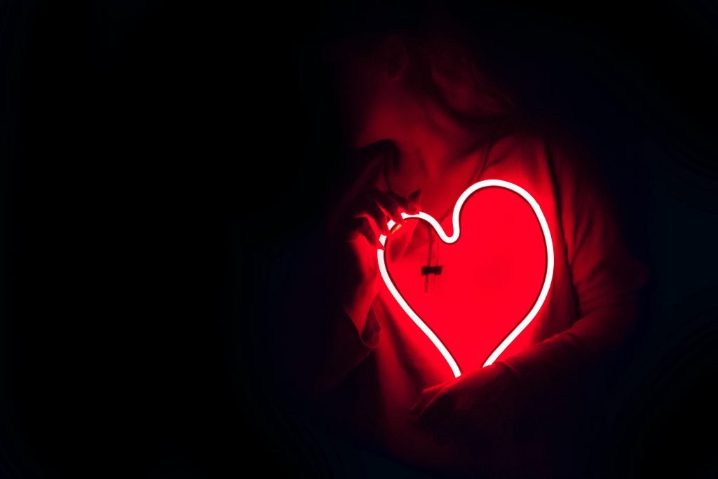 Person holding red neon heart light