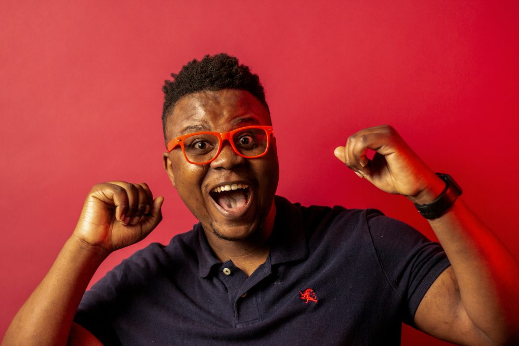 Cheering person wearing red glasses against red background