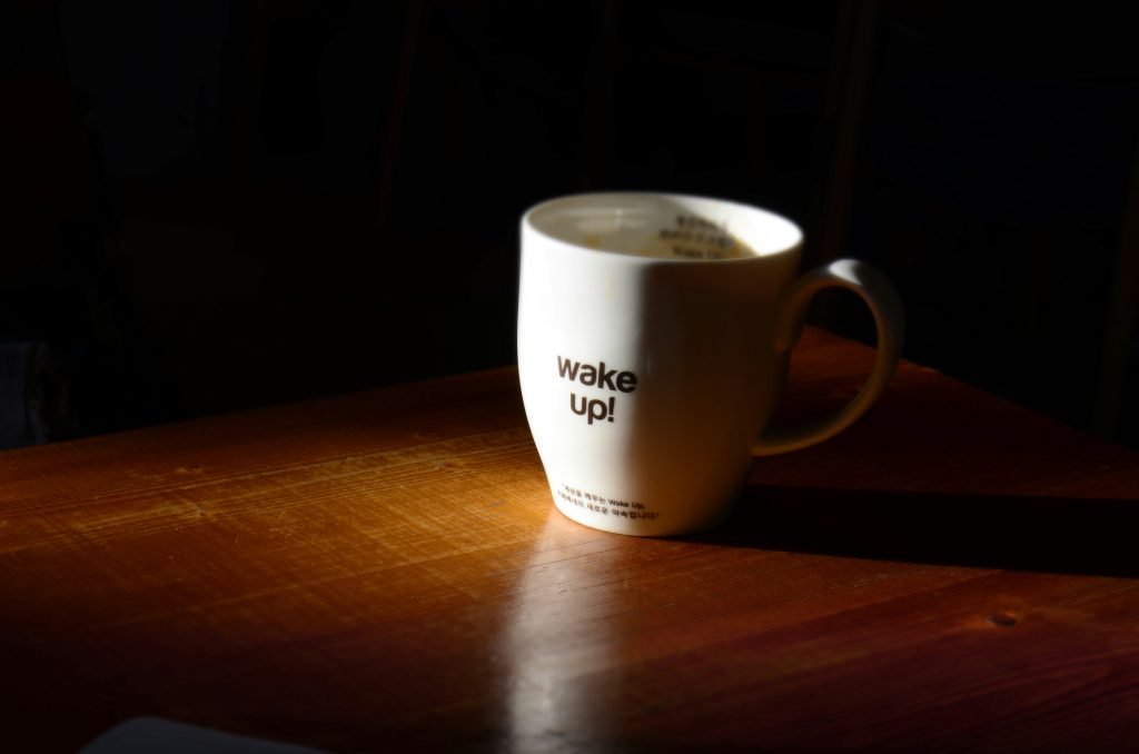 White mug with "wake up!" on wooden table