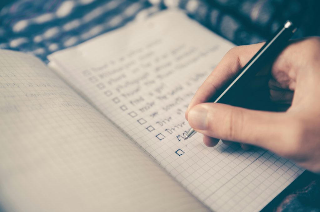 Hand checking items on notebook checklist