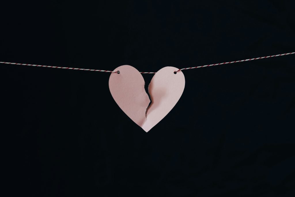 Torn pink paper heart hanging on string