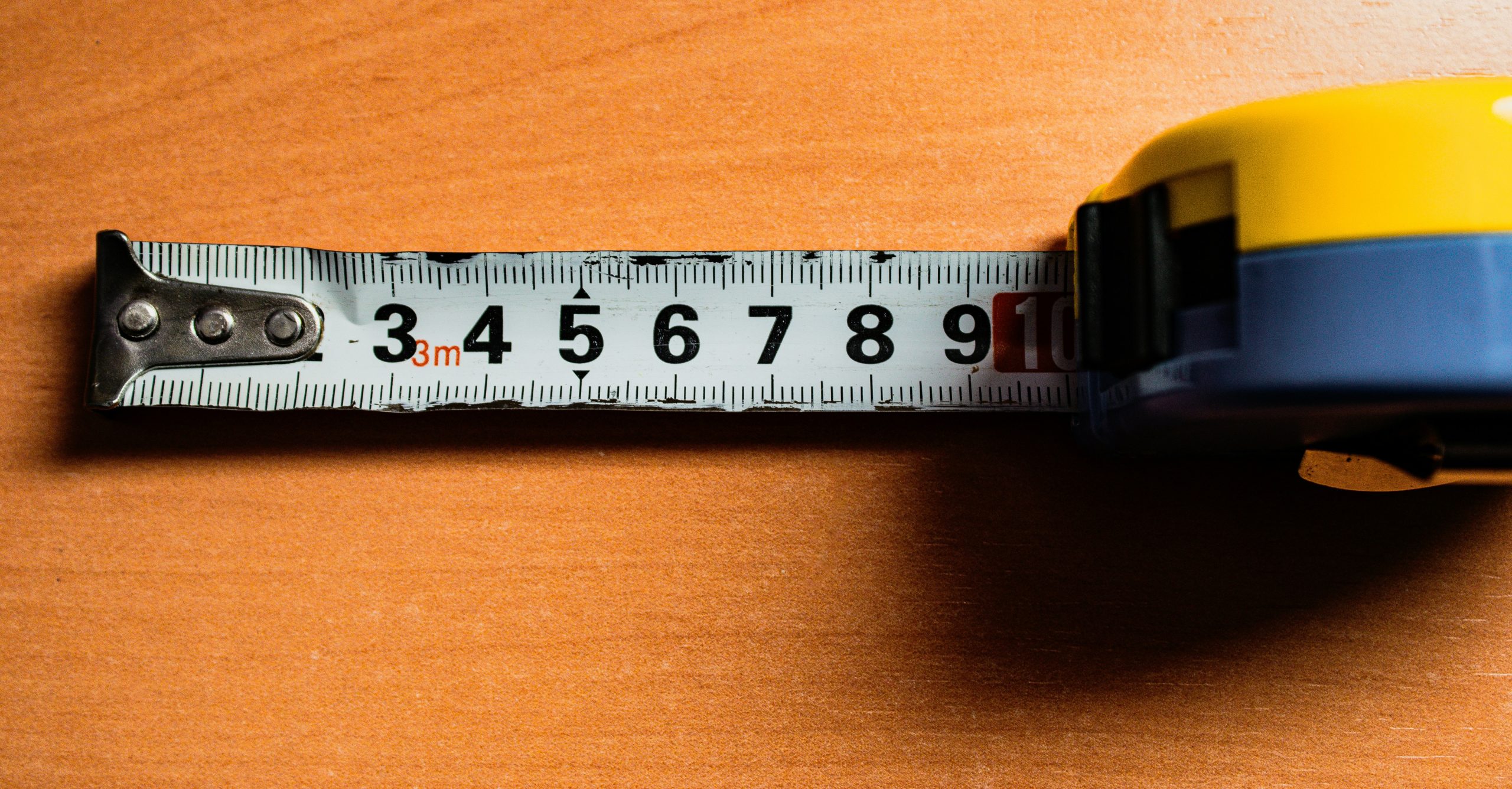 Yellow tape measure extended on wooden surface