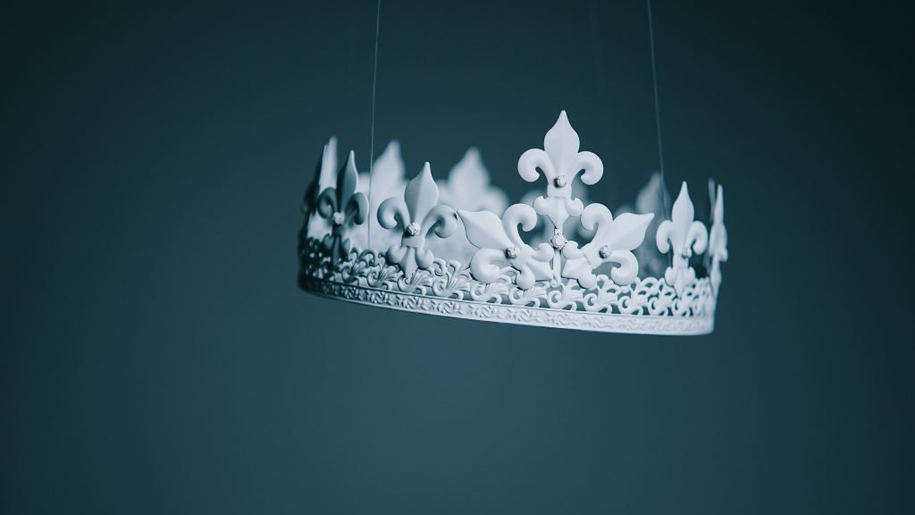Ornate white crown suspended against dark background