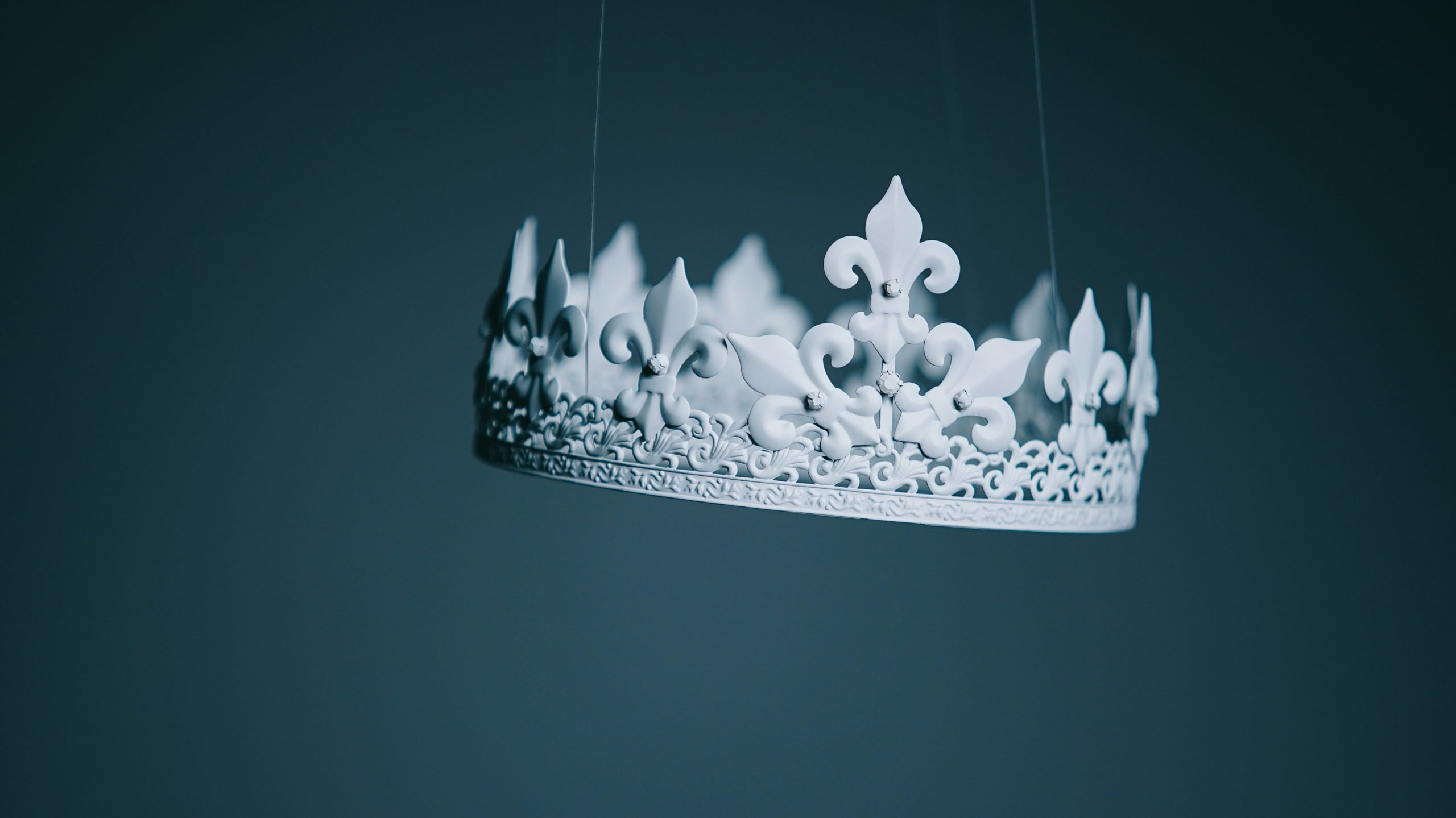 Ornate white crown suspended against dark background